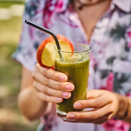 jugo de hierba de cebada deshidratado orgánico en vaso con pajita y decoración de manzana